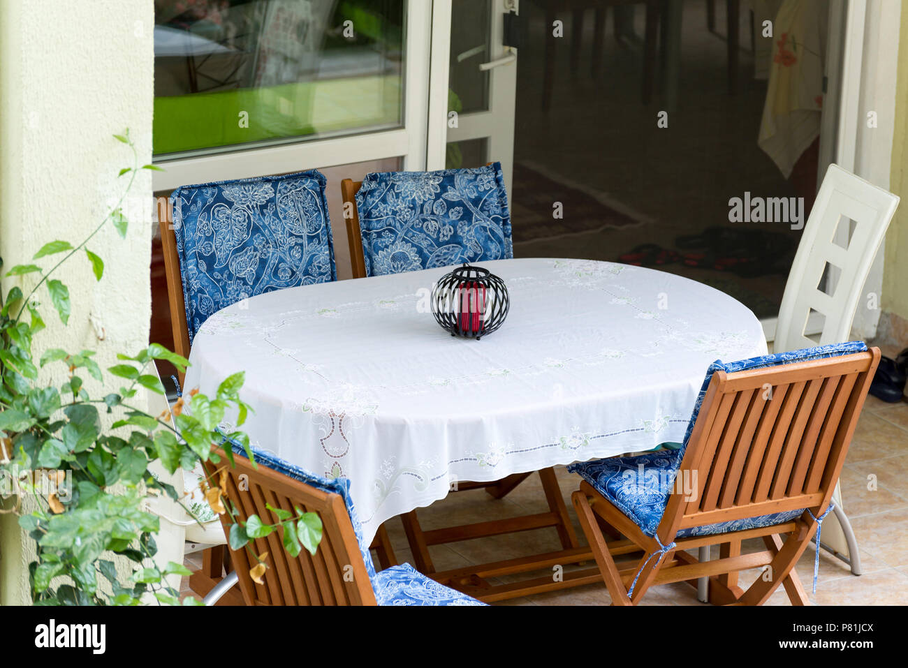 table covered with white tablecloth and chairs near house Stock Photo