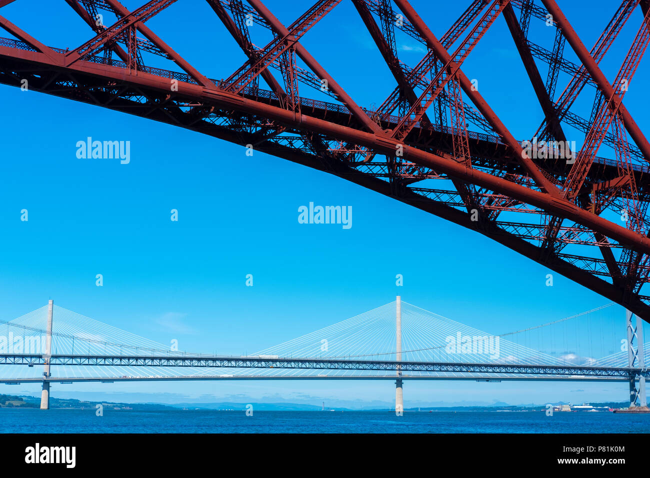 The Queensferry Crossing and the Forth Road Bridge,  seen from a pleasure boat on the Firth of Forth about to sail below the Forth Bridge, summer 2018. Stock Photo