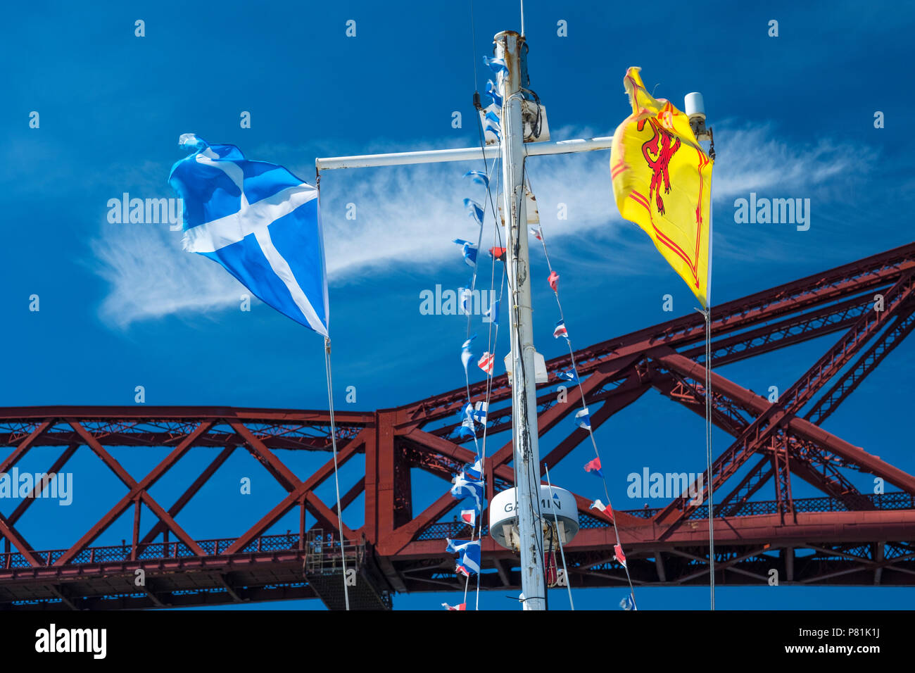 Saltire and Lion Rampant fluttering on a pleasure boat about to sail under the Forth Bridge at Queensferry, Scotland, summer 2018. Stock Photo