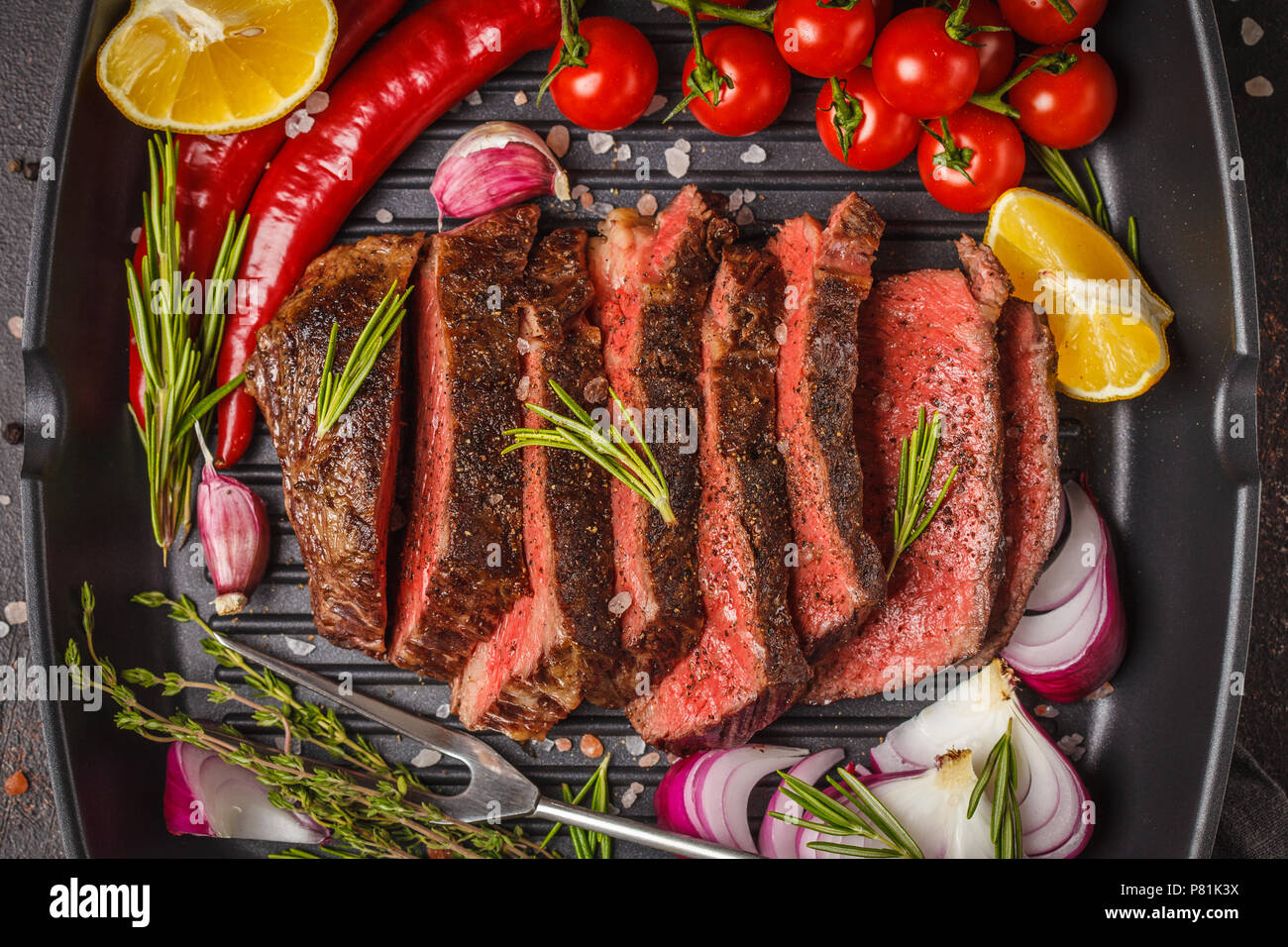 Sliced roast beef in a frying pan grill with spices and vegetables, top