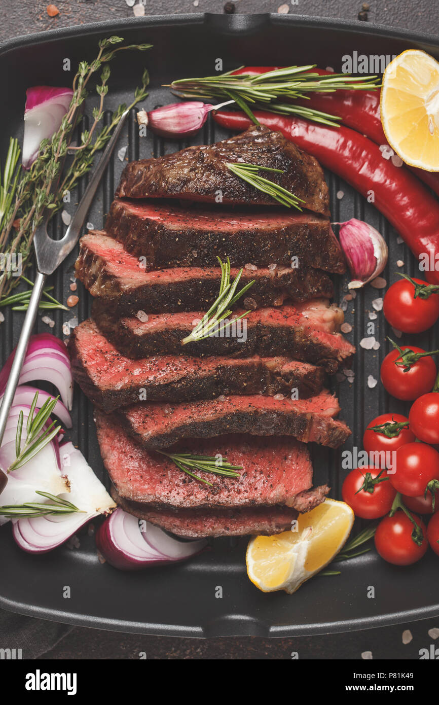 Sliced roast beef in a frying pan grill with spices and vegetables, top