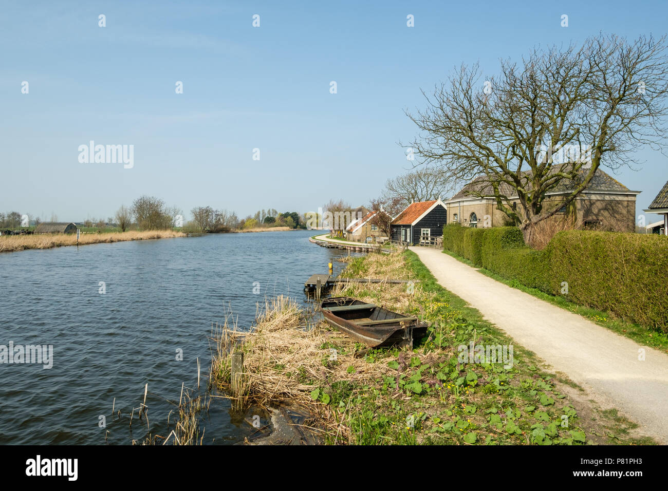 An historic polder pumping station on the right alongside the canal, Netherlands Stock Photo