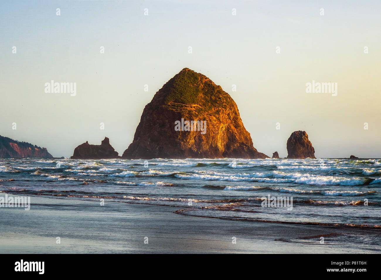 The Haystack Rock at high tide and at sunset. Famous and iconic sea stack located in Cannon Beach, Oregon, USA. Stock Photo