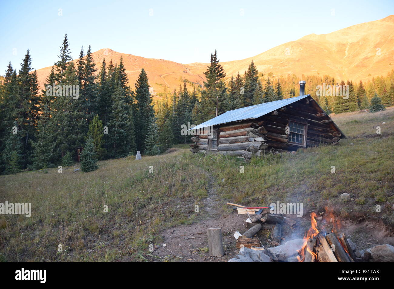 Building a Fire at a Log Cabin High in the Colorado Rockies during sunset Stock Photo
