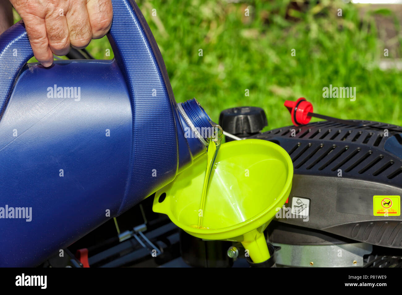 A man pours oil on his lawn mower using a funnel Stock Photo Alamy