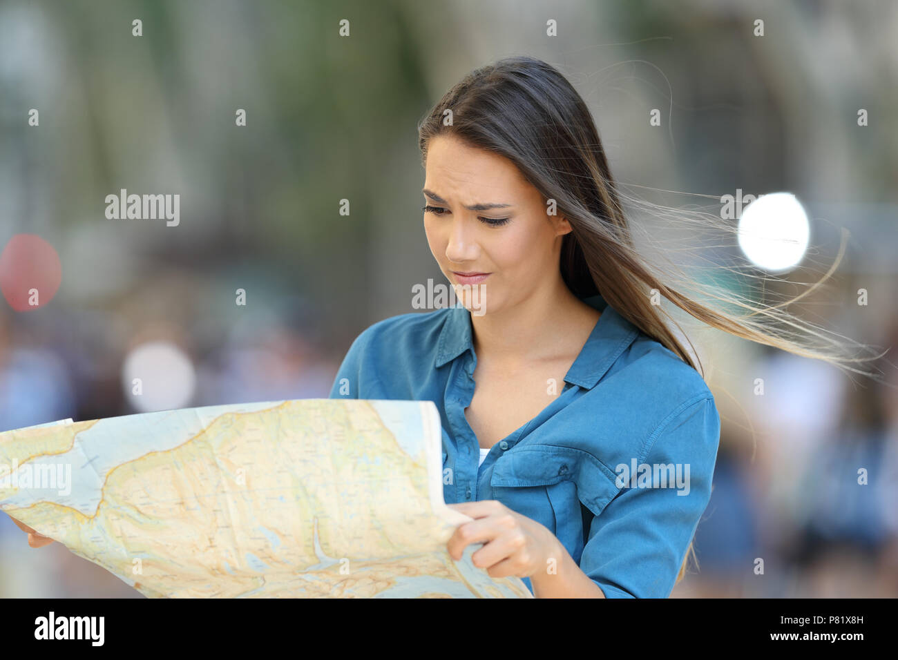 Confused lost tourist reading a map searching location on a city street Stock Photo