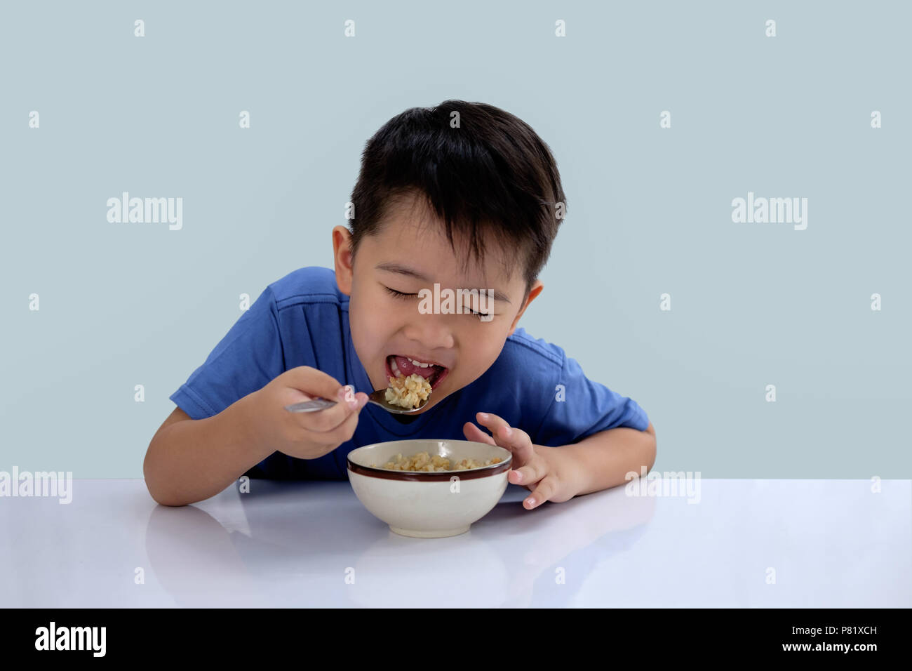 the Asian boy is eating delicious rice and has a very happy face. Stock Photo