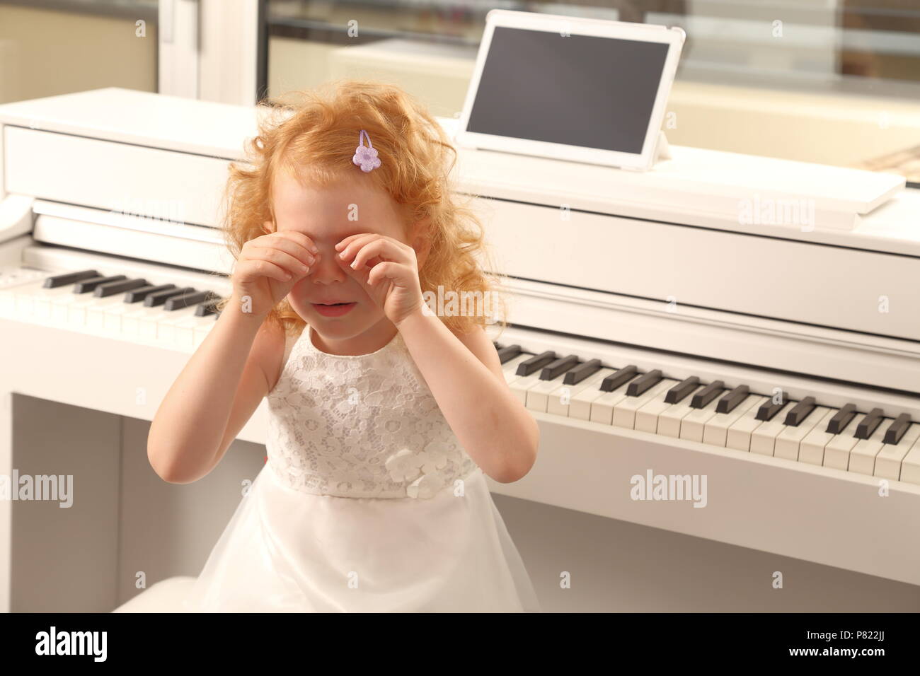 A Overwhelmed girl child crying at piano lesson Stock Photo