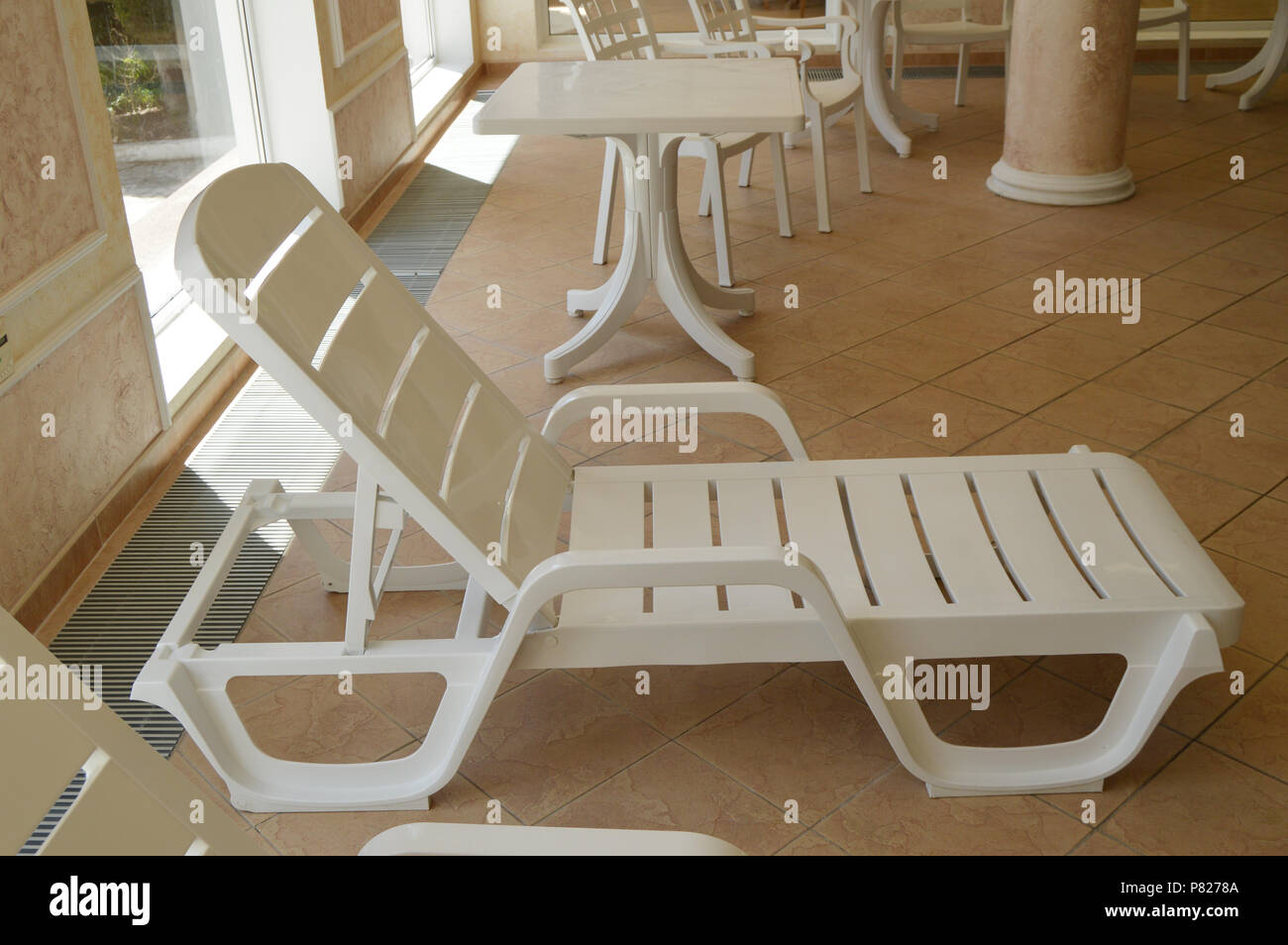 White plastic beach chair is inside the luxurious swimming pool Stock