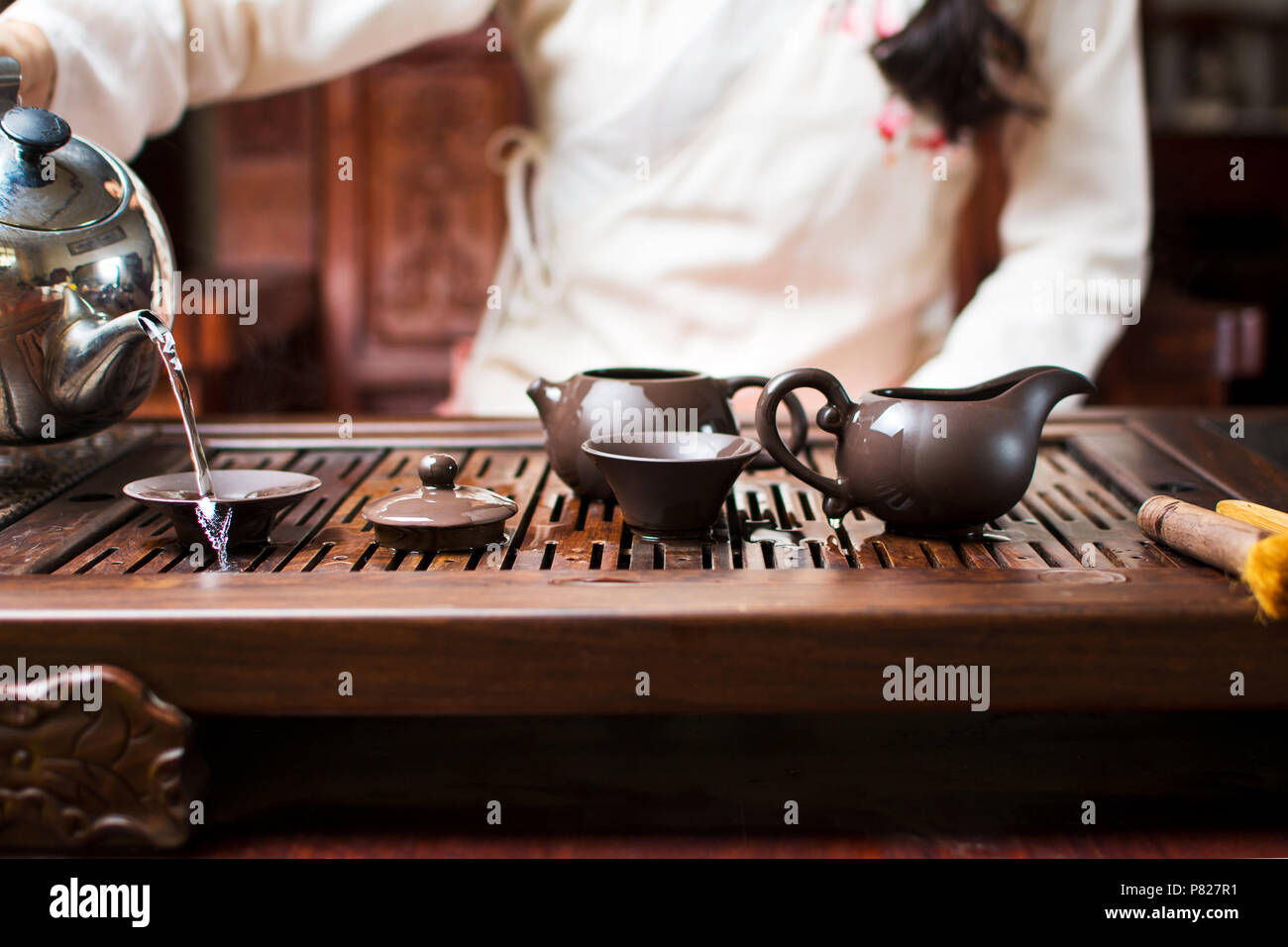 Woman cleaning tea cups and pots with boiled water during Chinese tea