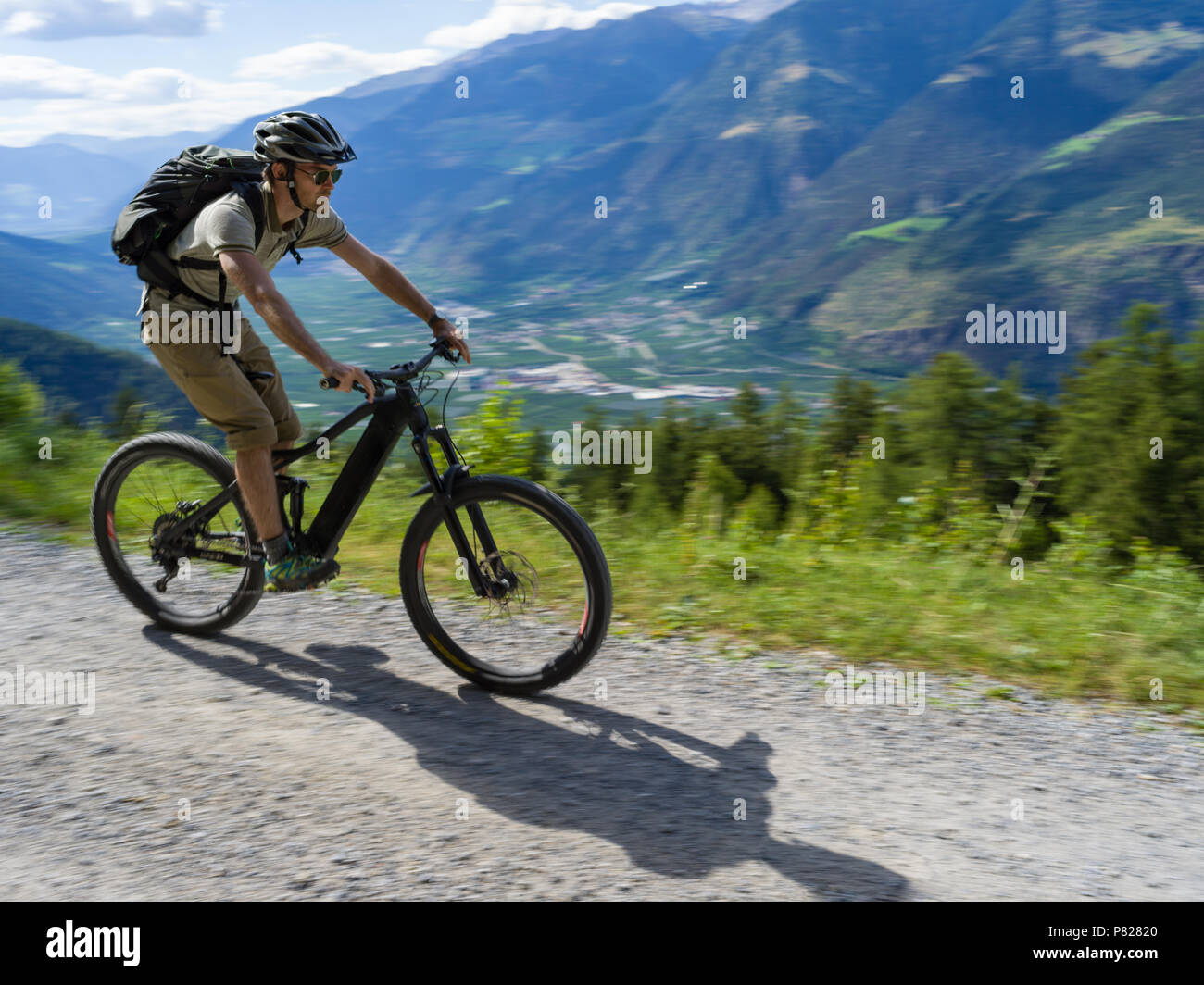 Casual Biker with e-Bike riding through Italian Alps Stock Photo