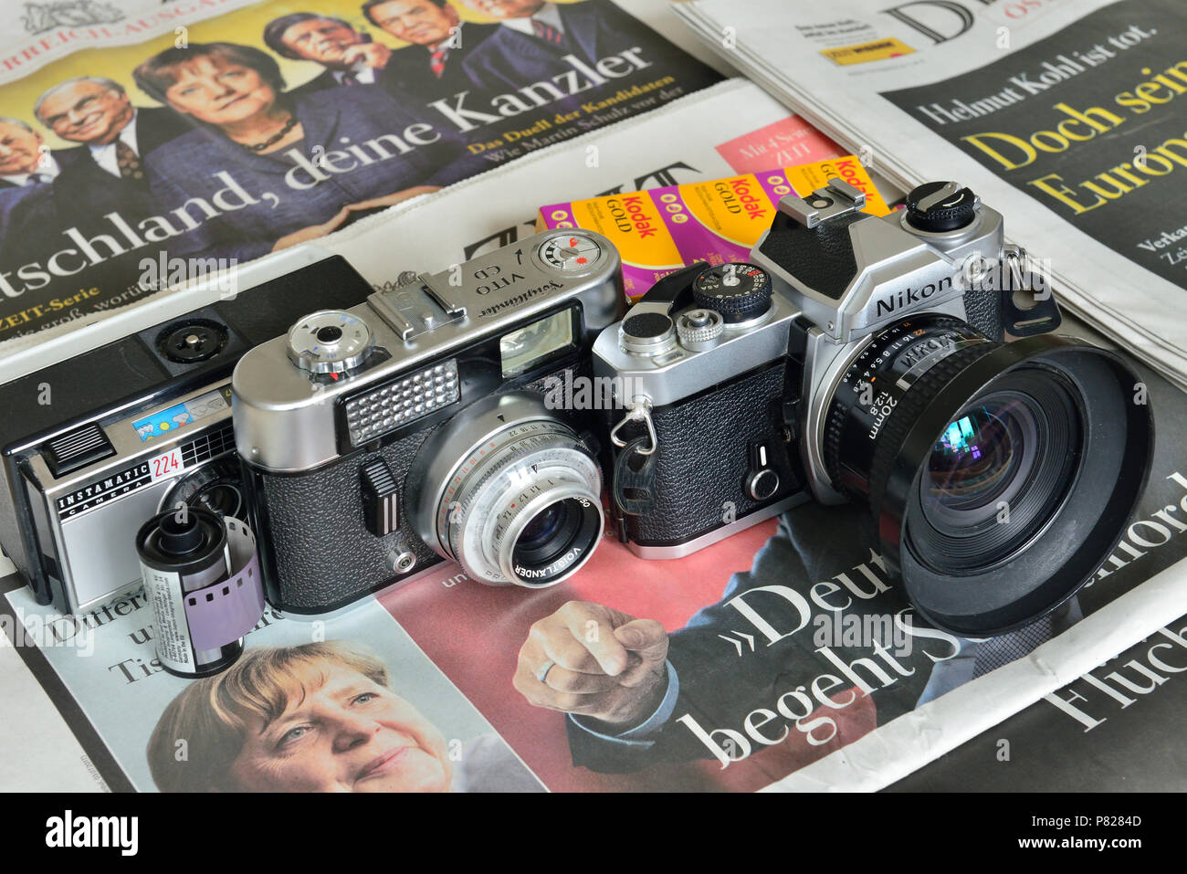 Analog cameras on newspapers. In the picture Nikon FM with 20 mm lens-Produced from 1977-1982, Voigtländer Vito CD-Produced from 1961-1966, and Kodak  Stock Photo