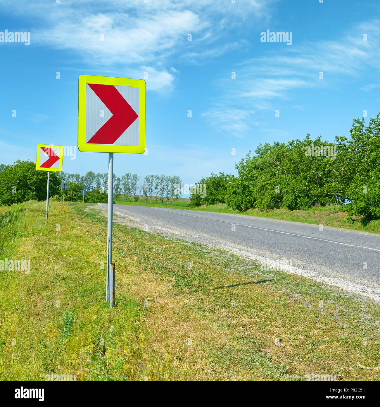 Warning signs for dangerous turn to right on country road. Stock Photo