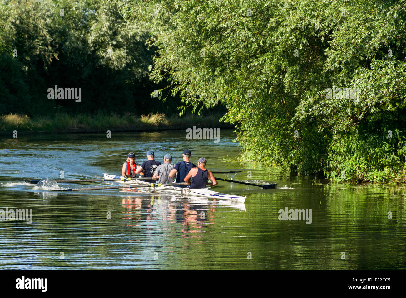 A four man row boat crew rowing down the river Cam on a sunny