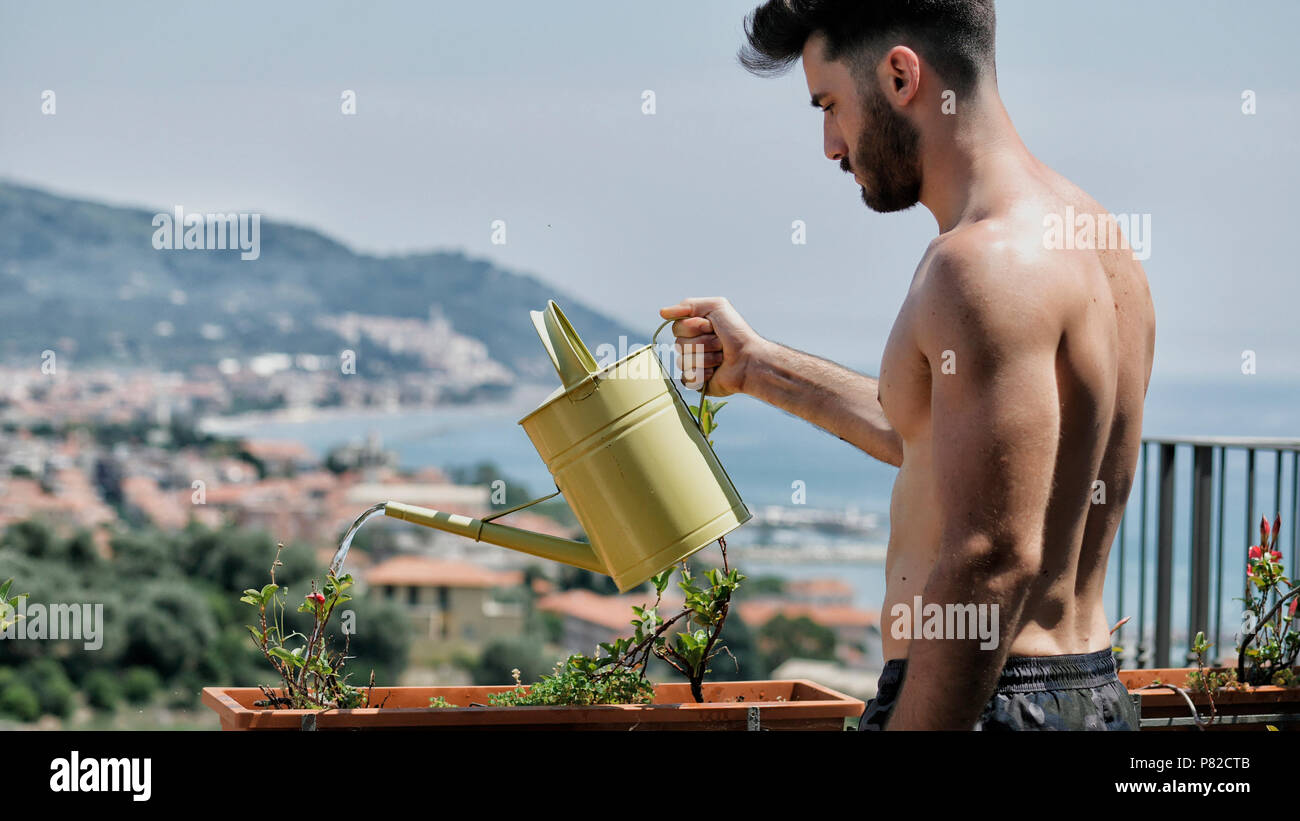 Young Man Watering Plants on Apartment Balcony Stock Photo Alamy