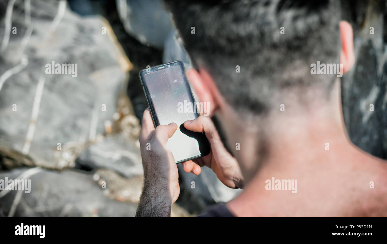 Young man using cell phone to send text message Stock Photo