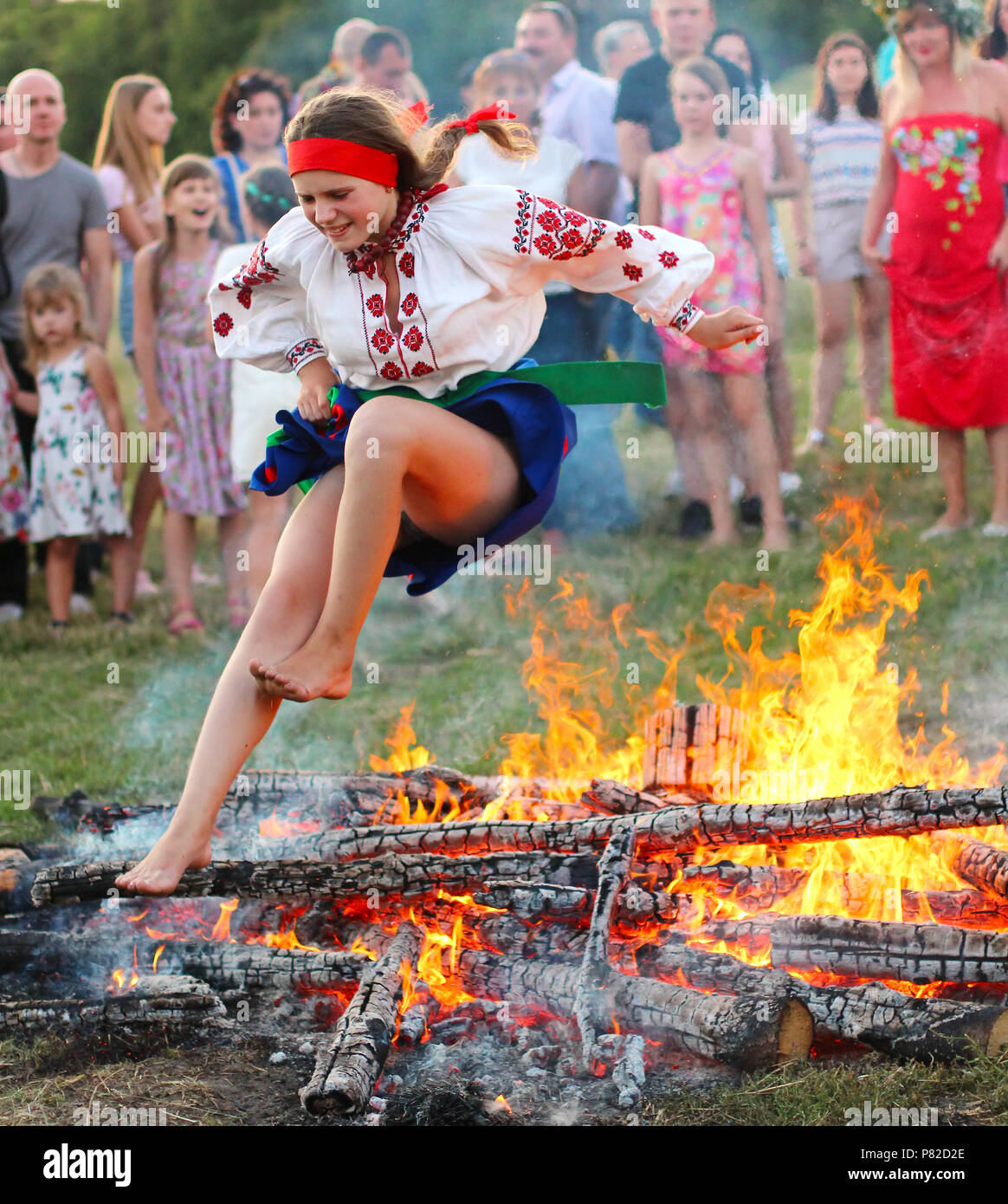 KYIV, UKRAINE - JULY 6, 2018: Young girl in national clothing jumps over the flames of bonfire during the traditional Slavic celebration of Ivana Kupa Stock Photo