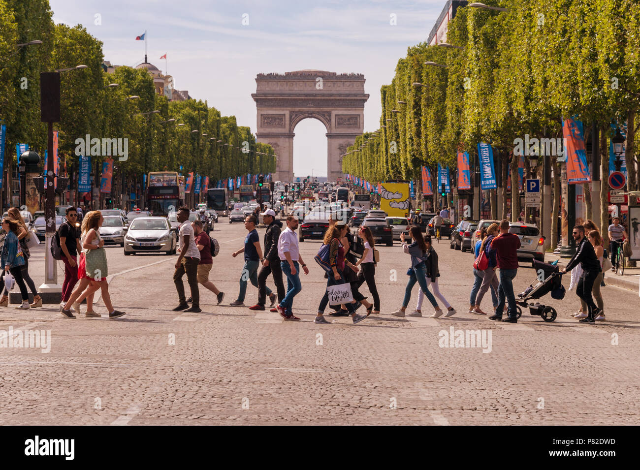 Paris, France - 23 June 2018: A crowd of people crossing Avenue des Champs-Elysees with Arc de Triomphe in the Background Stock Photo