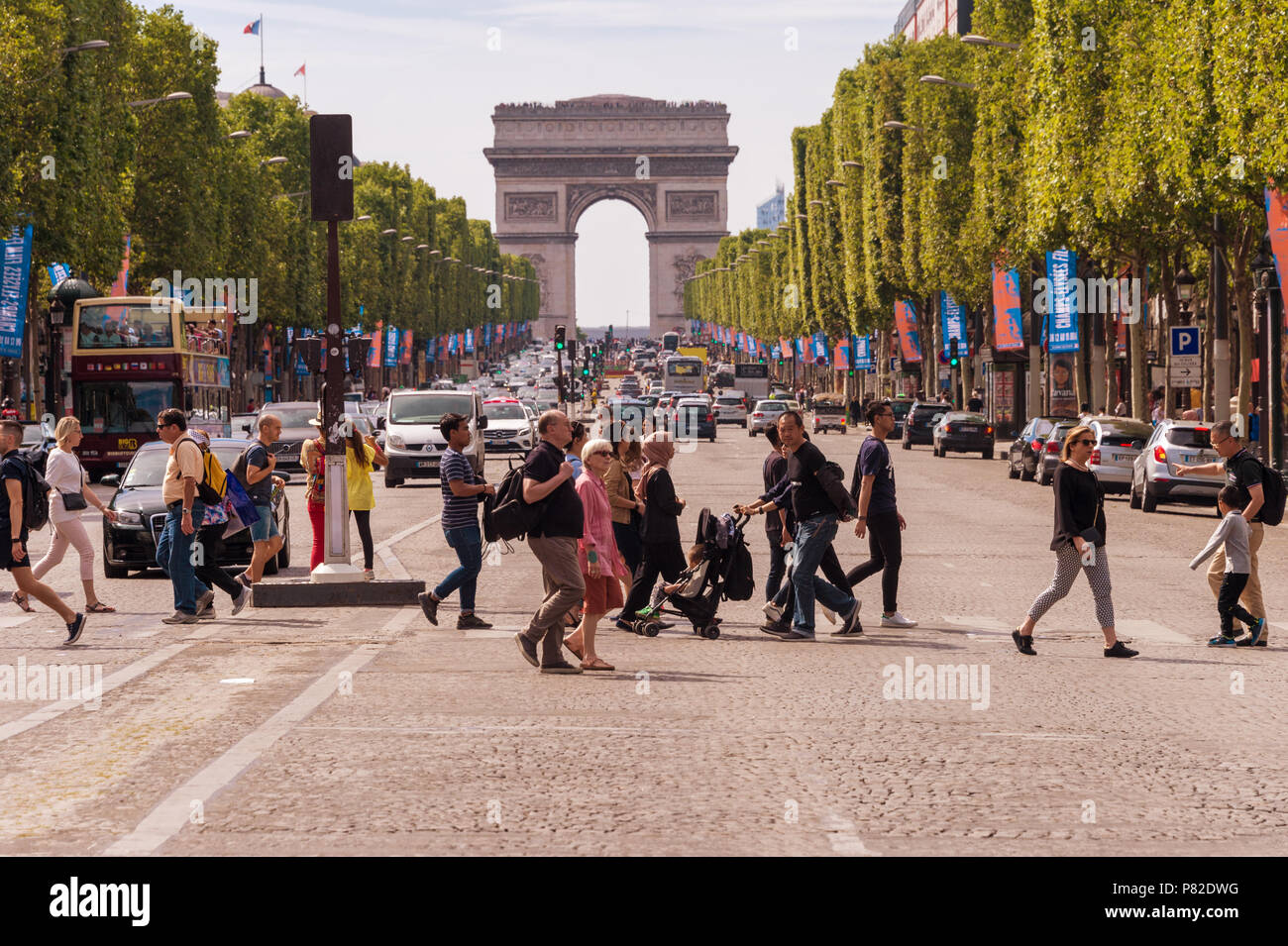 Paris, France - 23 June 2018: A crowd of people crossing Avenue des Champs-Elysees with Arc de Triomphe in the Background Stock Photo