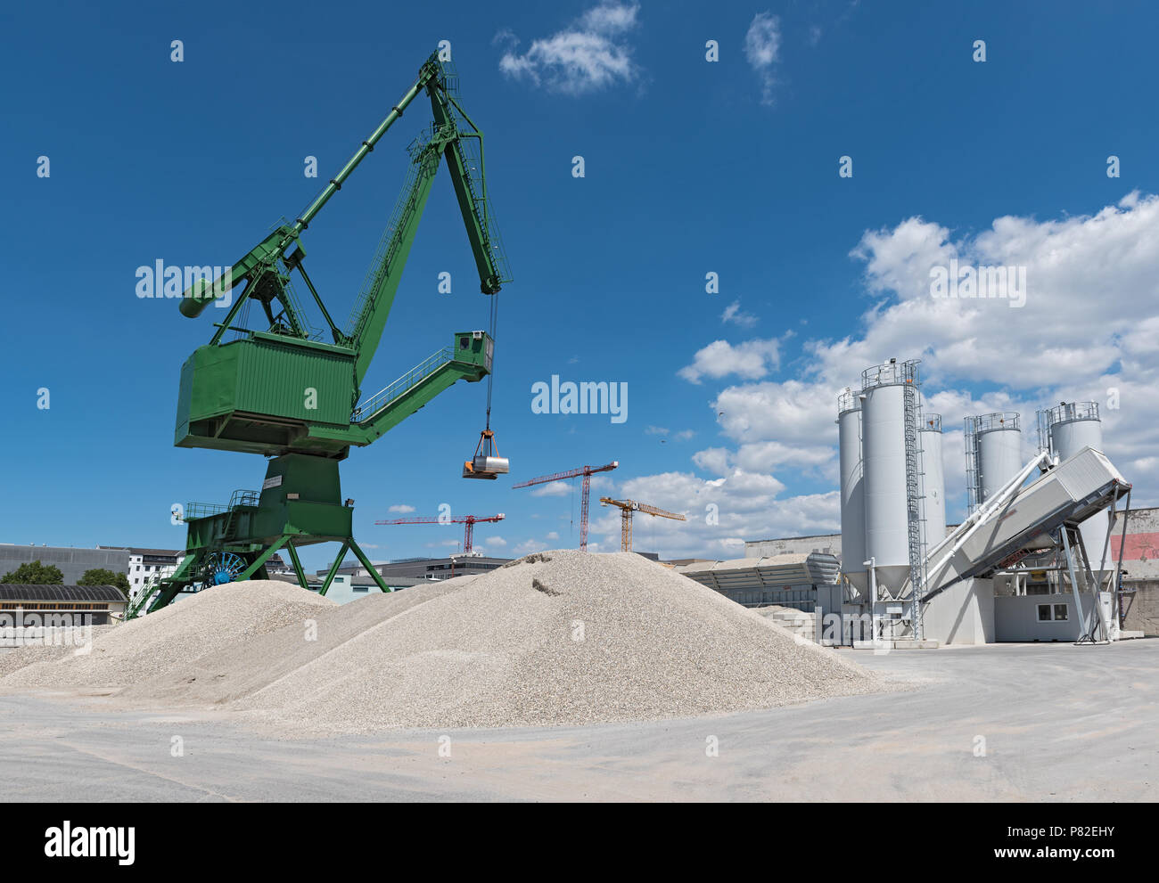 Exterior view of a cement factory with green crane. Stock Photo