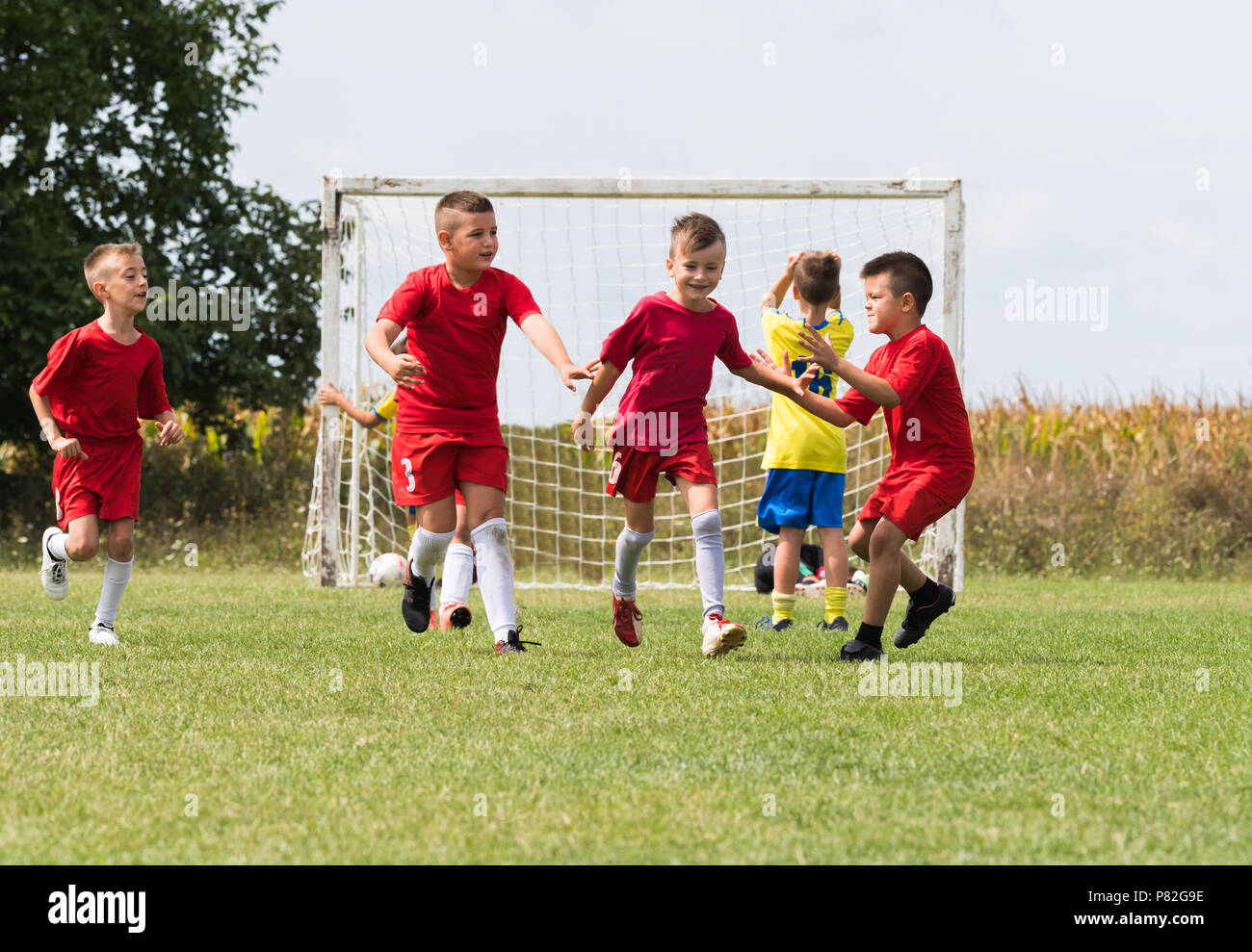 Kids soccer football - little children players celebrating after goal at  soccer field Stock Photo