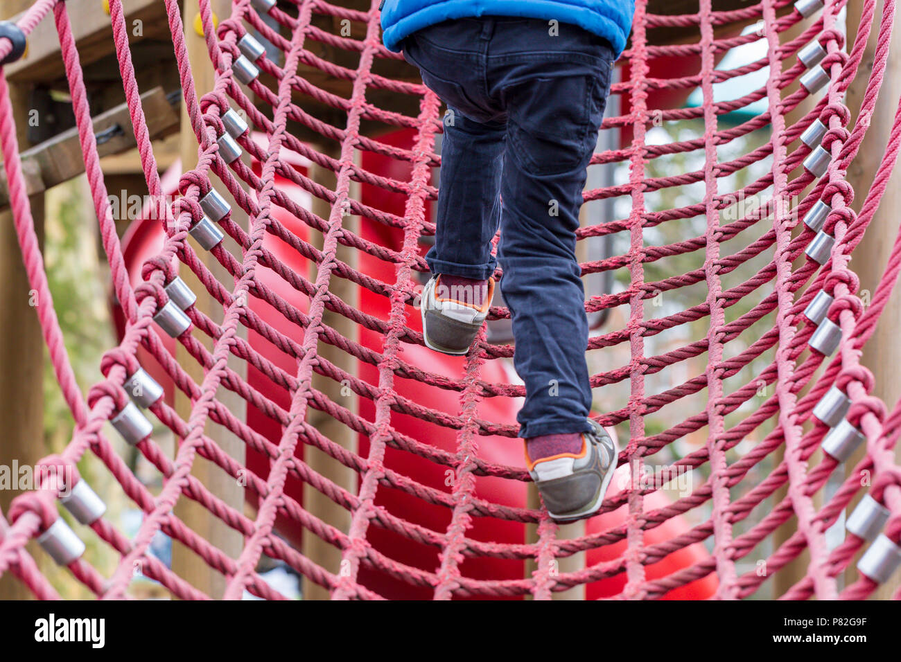 Young child playing on a rope climbing frame in Battersea Park, London