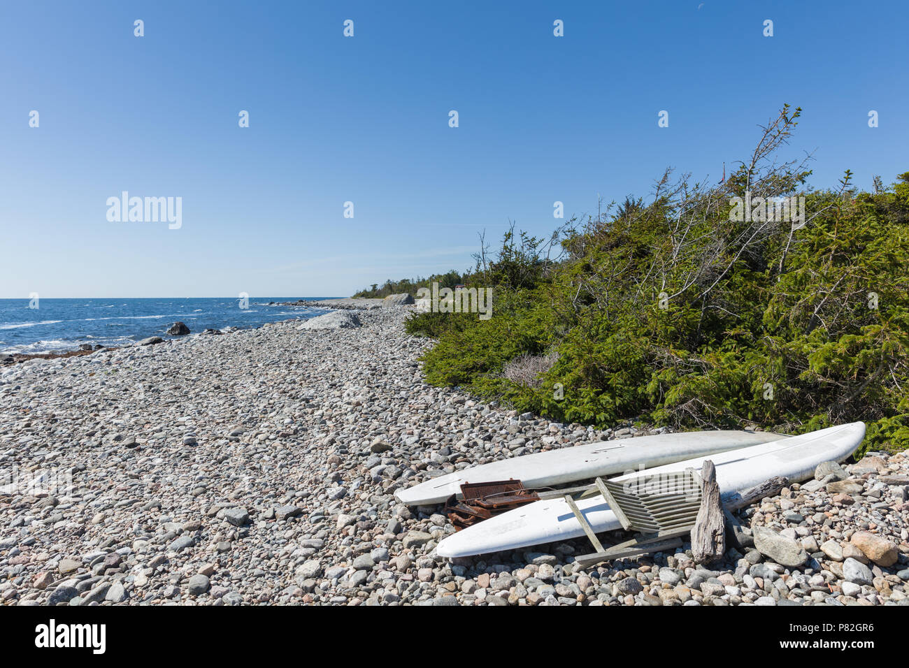 Old windsurfing boards found on a rocky beach. Stock Photo