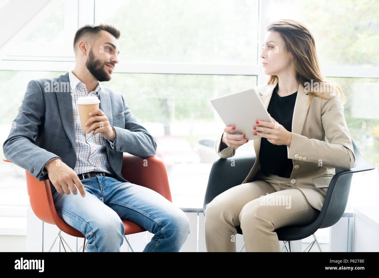 Two Modern Business People Relaxing in Chairs Stock Photo