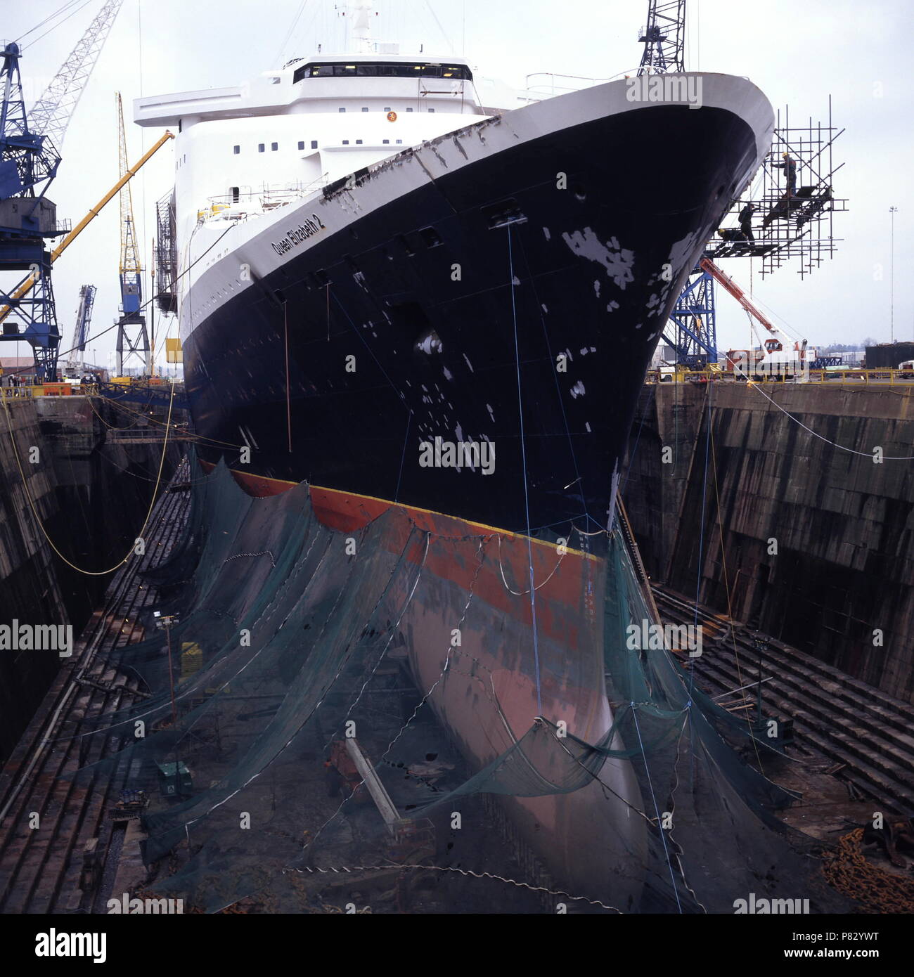 AJAXNETPHOTO. DEC 1996. SOUTHAMPTON, ENGLAND. -  BOW VIEW OF THE CUNARD PASSENGER LINER QUEEN ELIZABETH 2 - QE2 - IN KGV DRY DOCK, HER HULL SHROUDED IN NETTING, UNDERGOES REFIT.  PHOTO:JONATHAN EASTLAND/AJAX.  REF:1296 31 Stock Photo