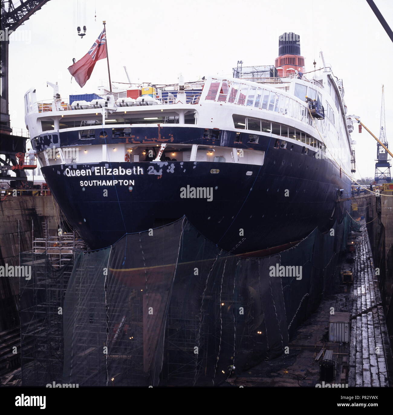 AJAXNETPHOTO. DEC 1996. SOUTHAMPTON, ENGLAND. - STARBOARD QUARTER VIEW OF  THE CUNARD PASSENGER LINER QUEEN ELIZABETH 2 - QE2 - IN KGV DRY DOCK, HER  HULL SHROUDED IN NETTING, UNDERGOES REFIT. PHOTO:JONATHAN