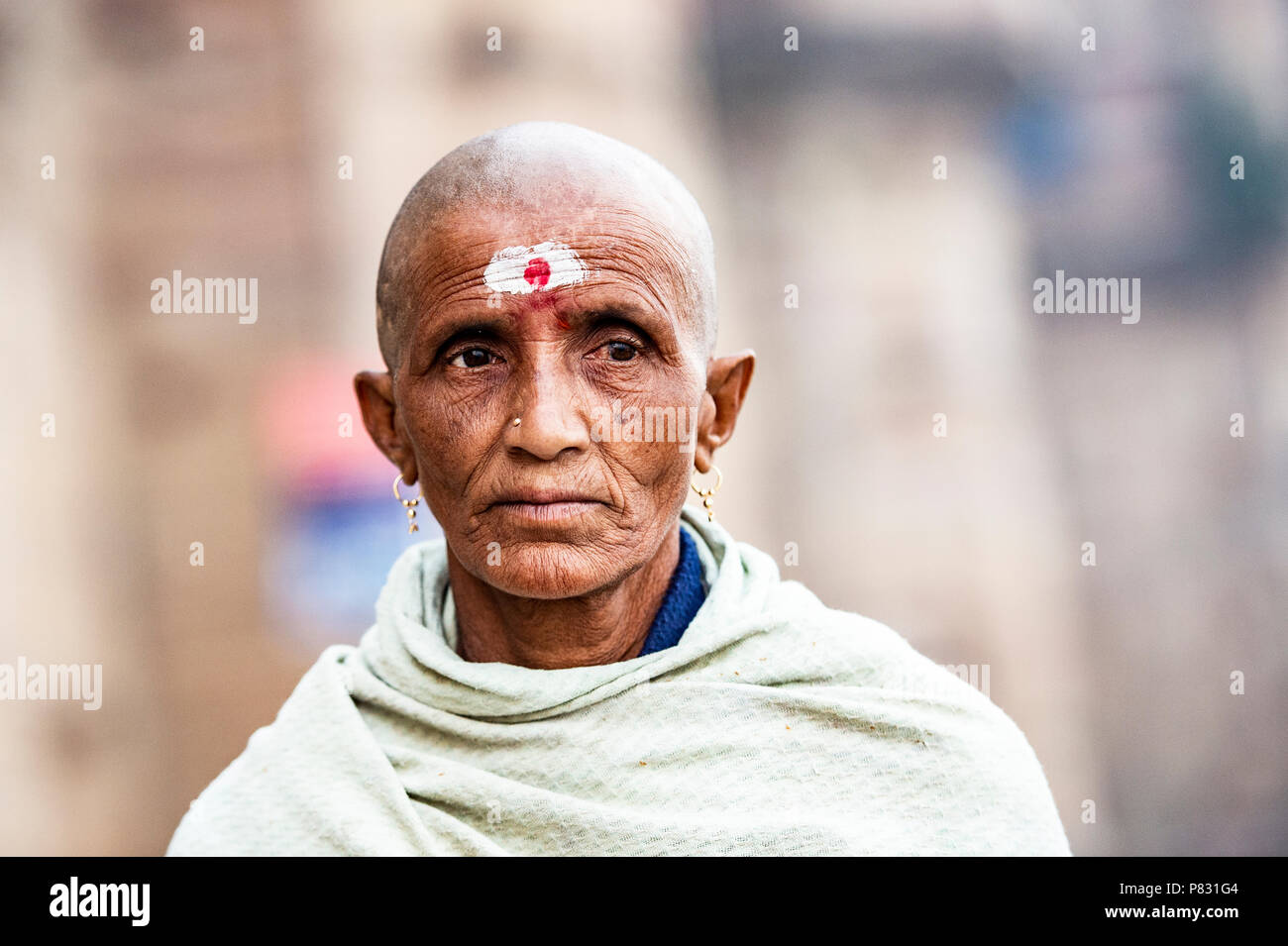 VARANASI - INDIA - 13 JANUARY 2018. Portrait of a sad and shaved old man walking on the ghat in Varanasi also known as Benares, India. Stock Photo