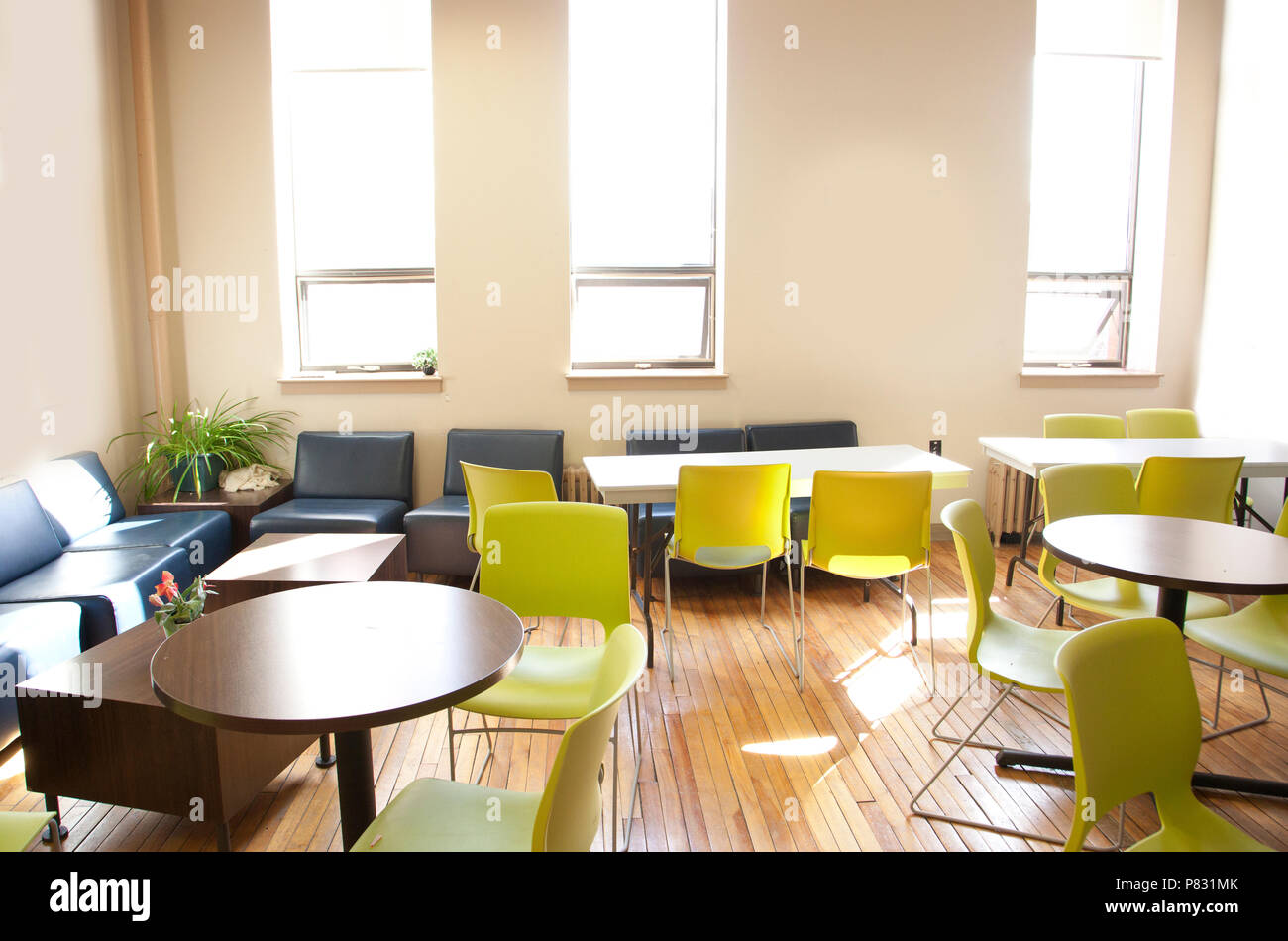 A brightly lit space with empty tables and chairs, ready for office