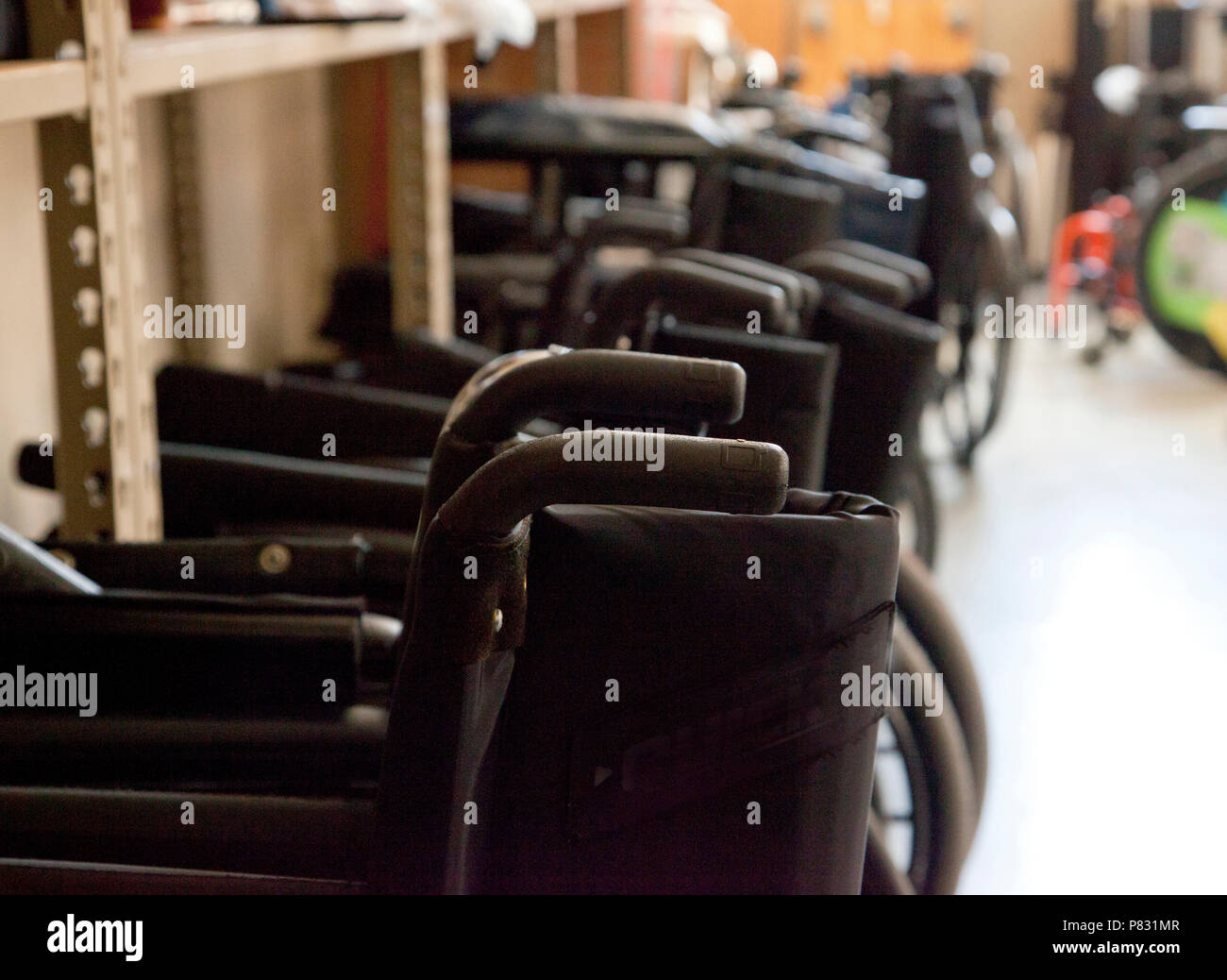 Black wheelchairs with handles lined up in a teaching clinic or ready