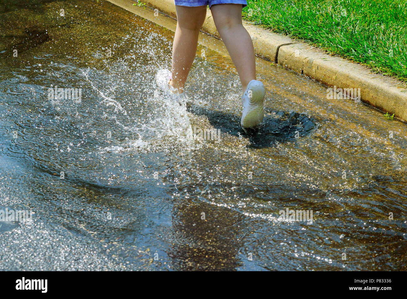 happy child girl rainy day in running and jumping in puddles after rain ...