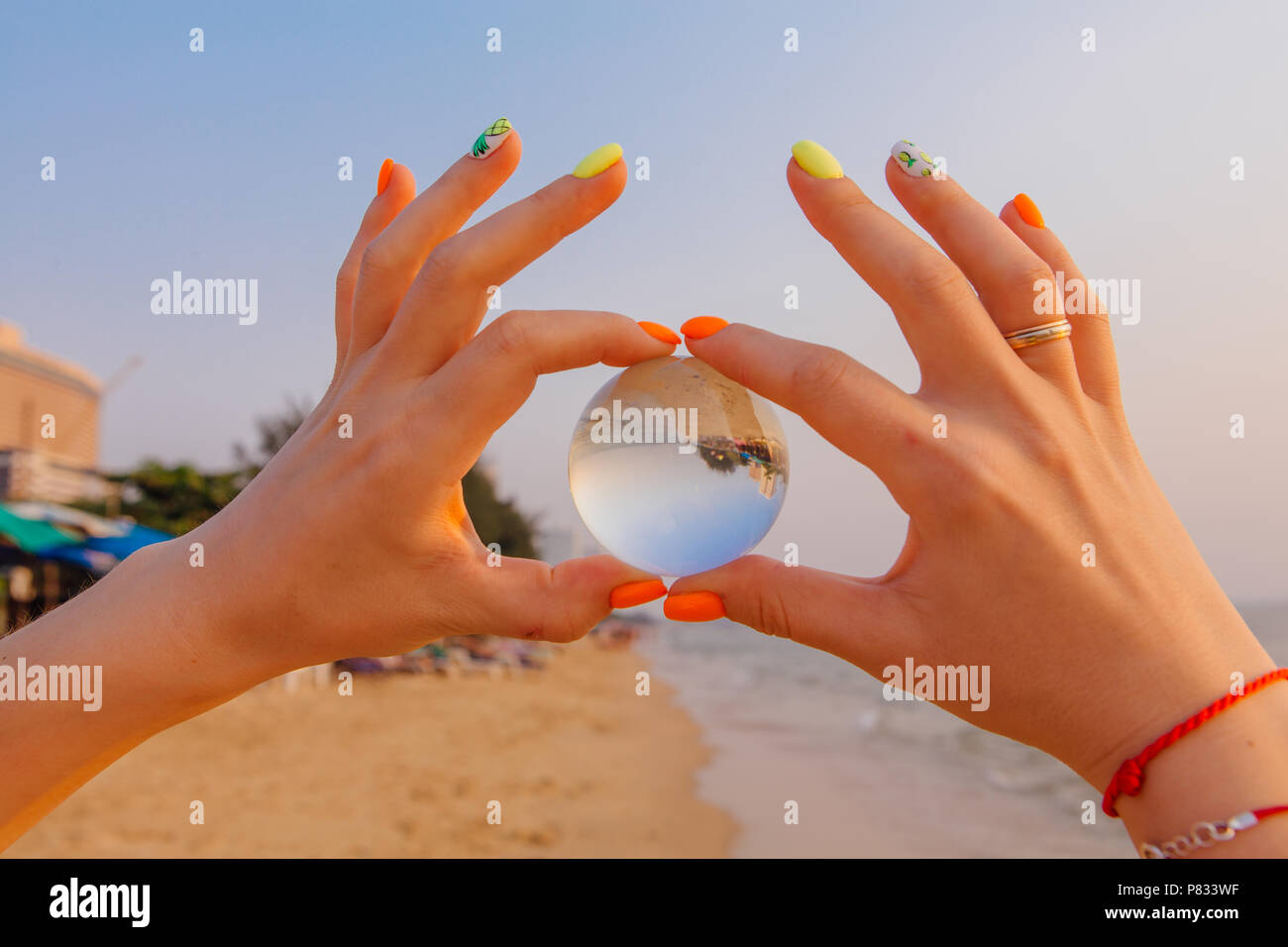 Crystal lens ball in hand with reflection of sea and sunset on the ...