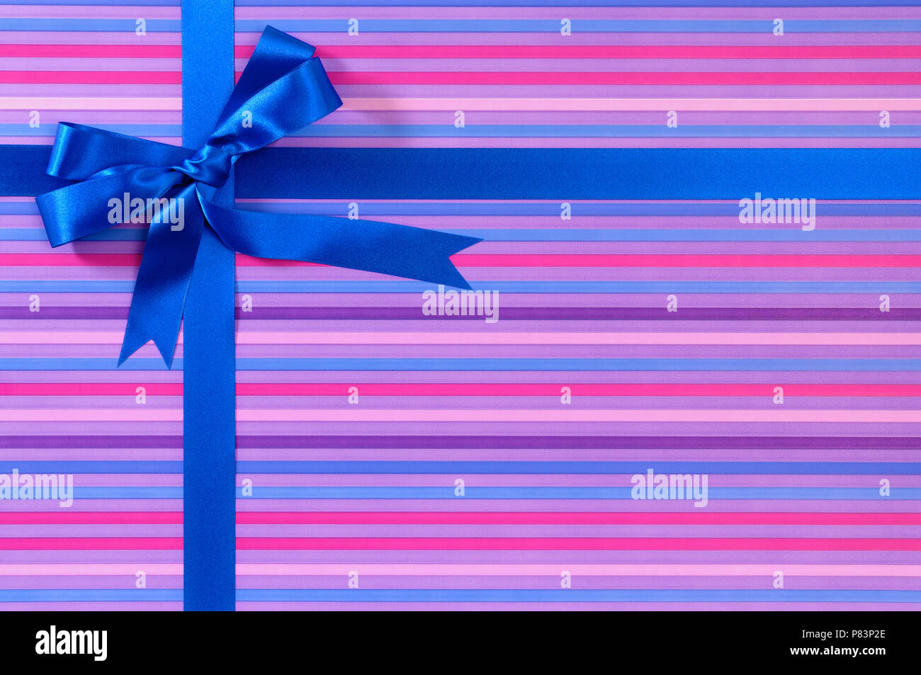 Blue Christmas or birthday gift ribbon bow on candy stripe wrapping paper background Stock Photo