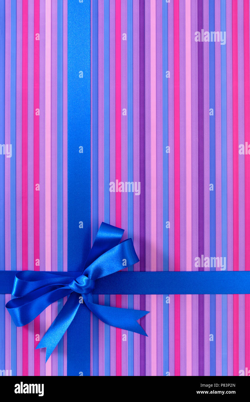 Blue gift ribbon bow on candy stripe wrapping paper background, vertical Stock Photo