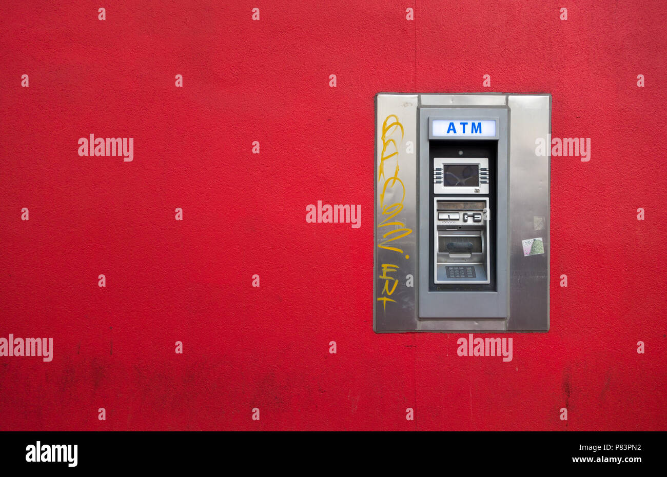 An automated teller machine (ATM) is a stark contrast on the bright red wall where it is mounted.  Toronto, Ontario, Canada Stock Photo