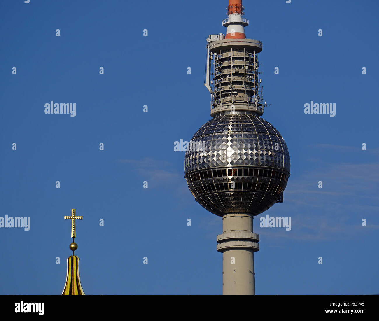 Sunlight forms cross on Berlin Communication Tower known as 'Pope’s Revenge.'  The cross of nearby Catholic Cathedral is in foreground. Stock Photo