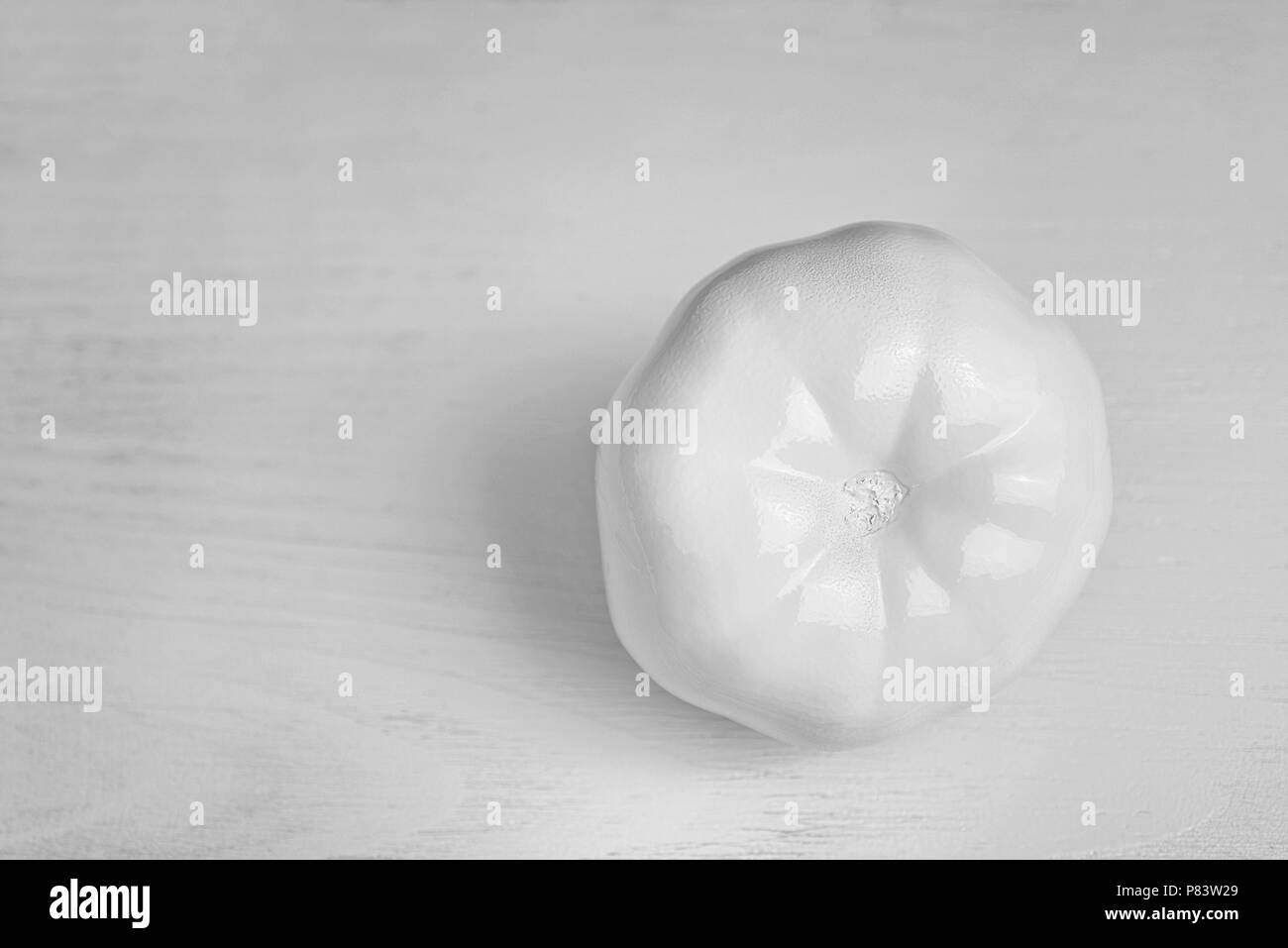 conceptual decoration of a cafe: white painted tomato on wooden background. Black and white vintage color designed vegetable Stock Photo