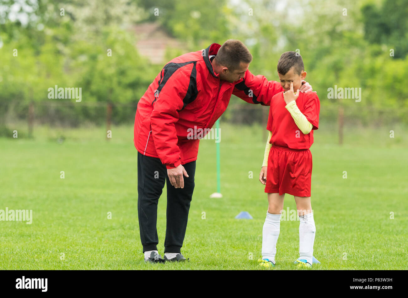 Kids soccer football - coach comfort little soccer player who is crying  after a missed goal Stock Photo - Alamy