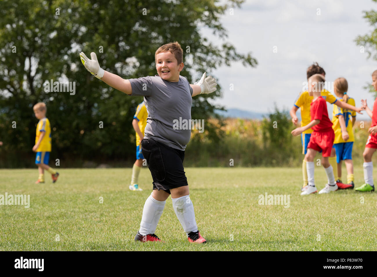 Kids soccer - Little goalkeeper is celebrating after successful football match at sports field Stock Photo
