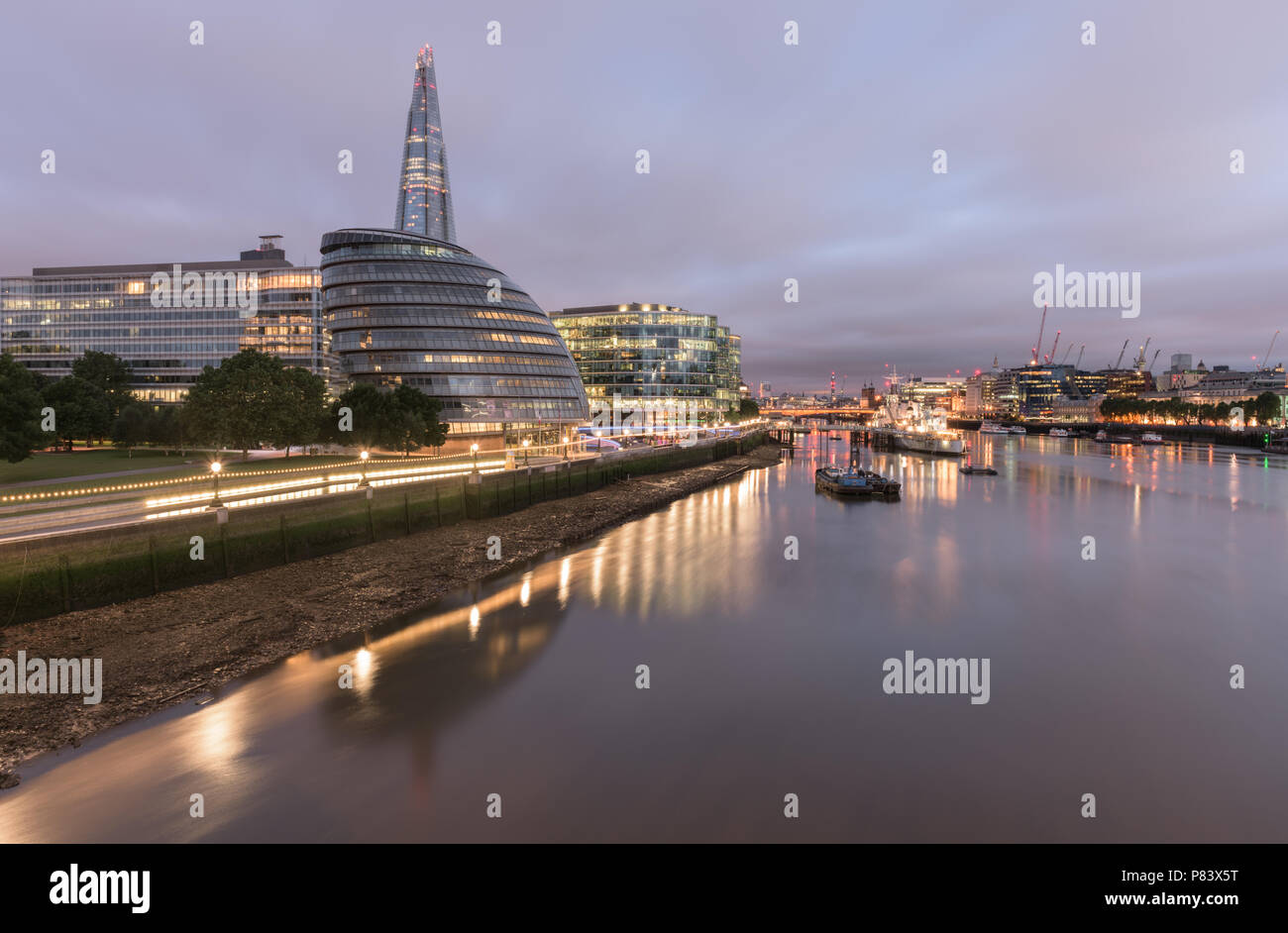 View from Tower Bridge to London Bridge down the River Thames with The Shard, City Hall and HMS Belfast lit up at dawn Stock Photo