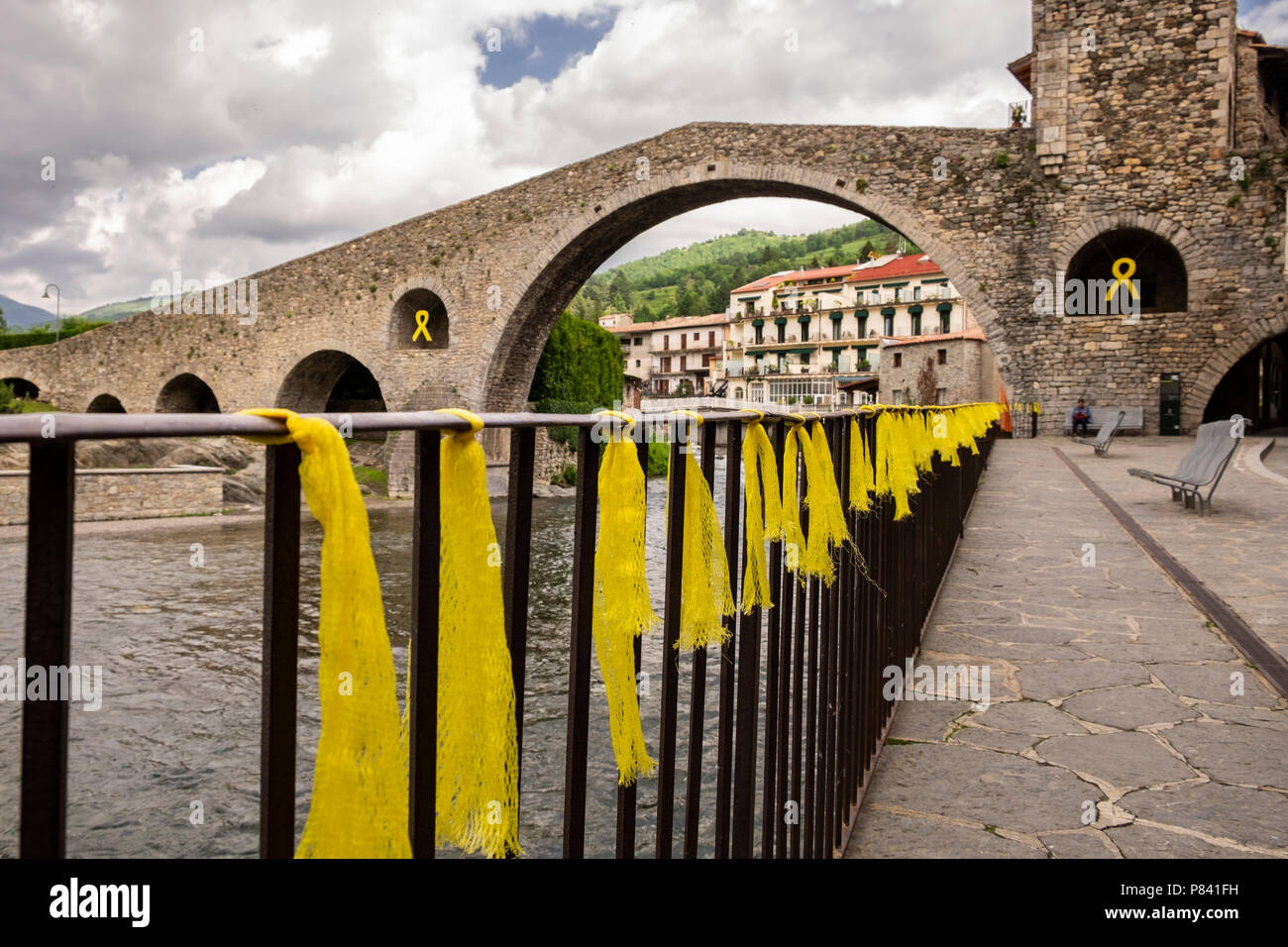 Pont Neu, the 12th century humpbacked bridge over the River Ter in Camprodon village with yellow streamers tied as a symbol of Catalonian independance Stock Photo
