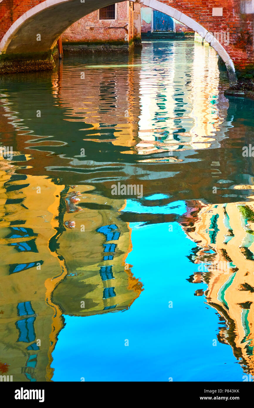 Venetian mirror - Houses, blue sky and small bridge reflect in the water of canal. Venice in water reflections Stock Photo
