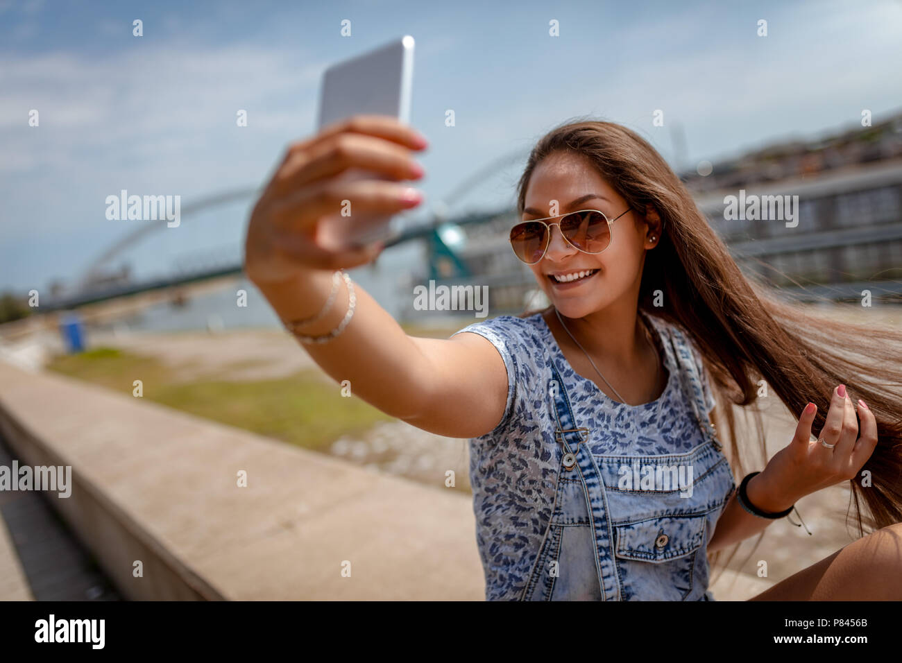 A beautiful cheerful girl taking a selfie and enjoying on the city ...