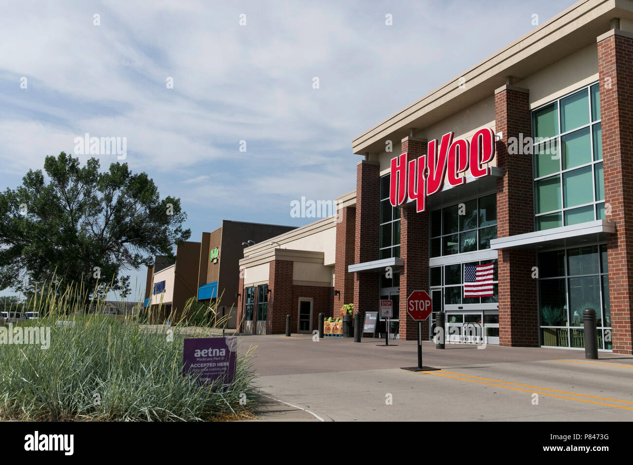 A logo sign outside of a HyVee retail grocery store in West Des Moines