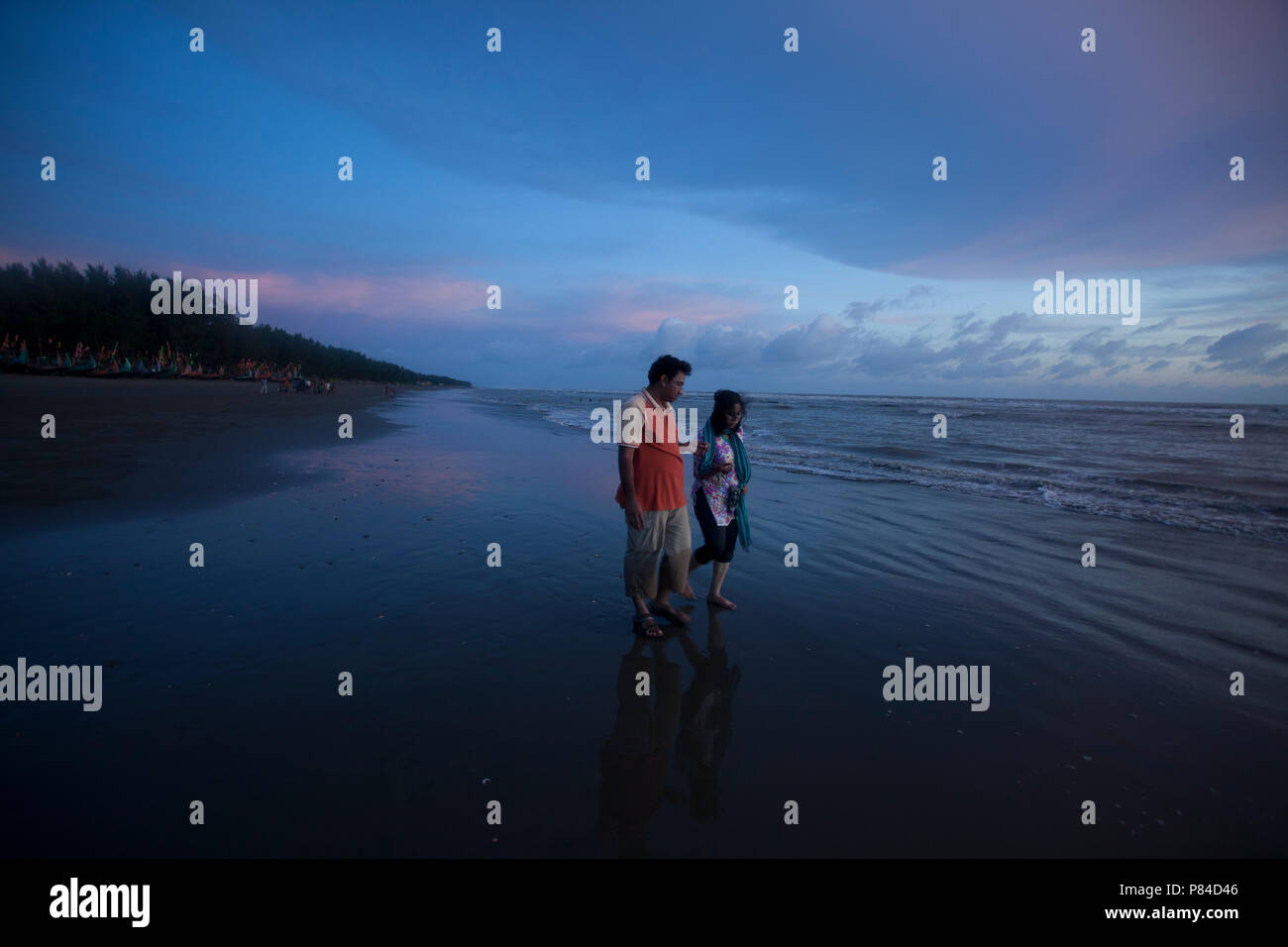 A couple roams at the Teknaf Sea Beach. It is a part of the Cox's Bazaar Sea Beach, the longest sea beach in the world. Teknaf, Cox´s Bazar, Banglades Stock Photo