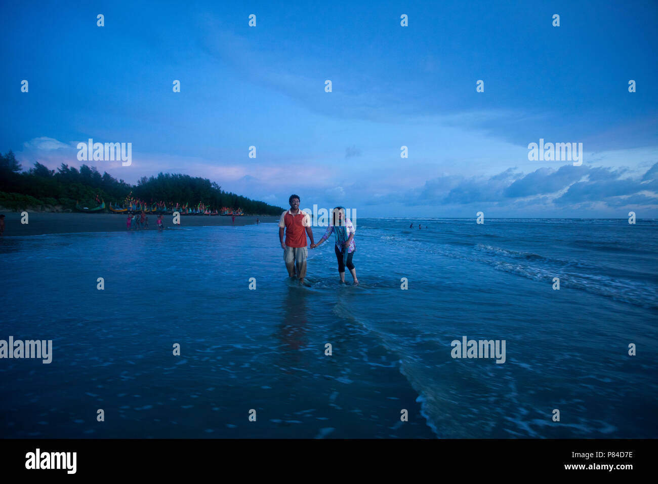 A couple roams at the Teknaf Sea Beach. It is a part of the Cox's Bazaar Sea Beach, the longest sea beach in the world. Teknaf, Cox´s Bazar, Banglades Stock Photo