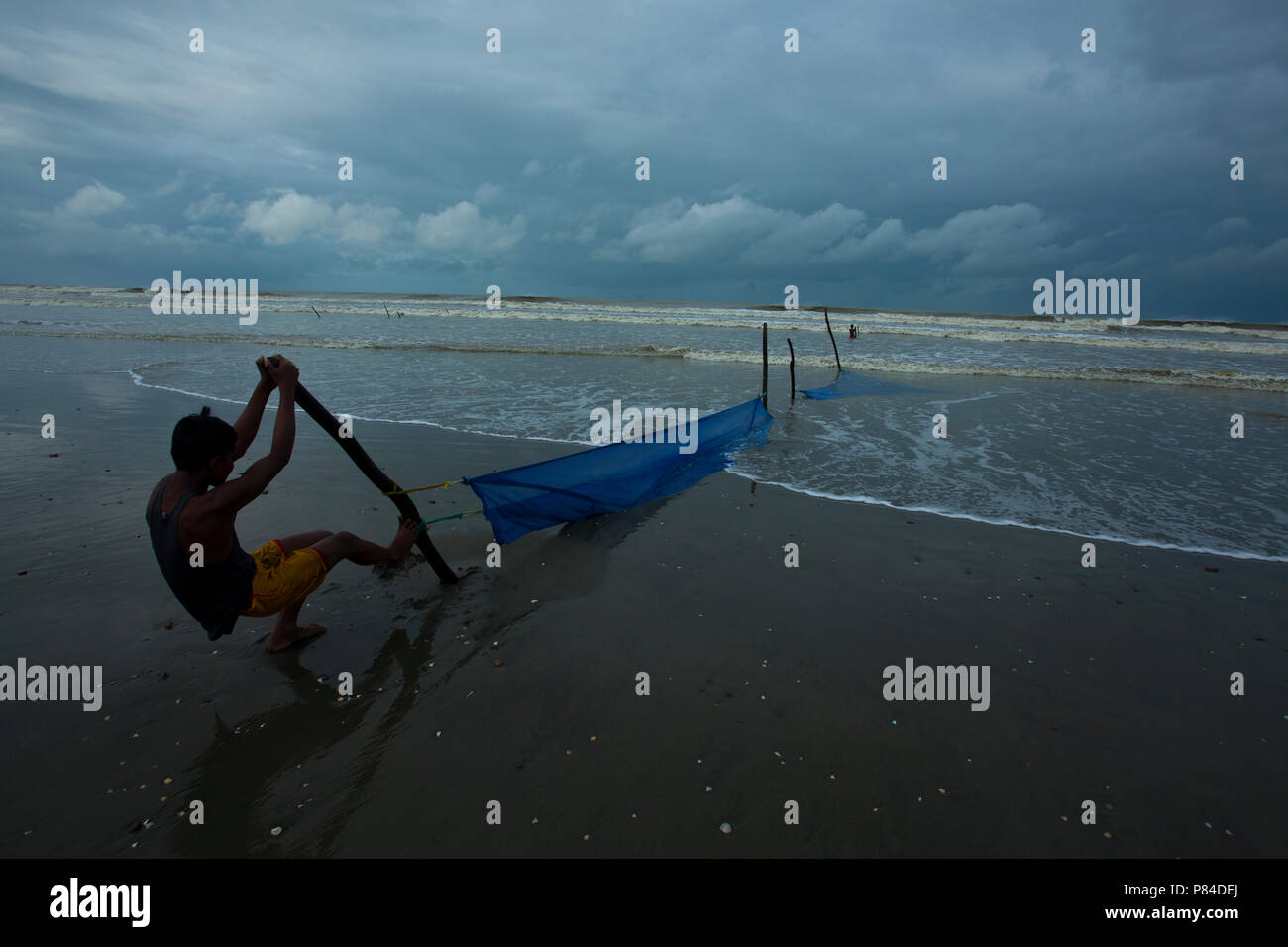 A fisherman places his net at the Teknaf Sea Beach. It is a part of the Cox's Bazaar Sea Beach, the longest sea beach in the world. Teknaf, Cox´s Baza Stock Photo